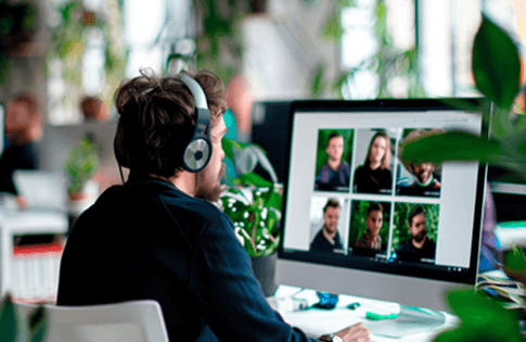 Man working remotely with a video call on his computer screen, eS branding visible.